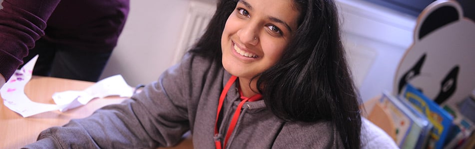 Female student sat in classroom smiling